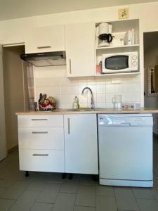 a kitchen with white cabinets and a sink and a dishwasher at Escapade à Pornichet/Wi-fi/Parking/Bord de Mer in Pornichet