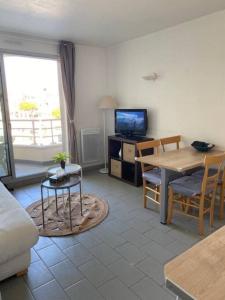 a living room with a table and a tv at Escapade à Pornichet/Wi-fi/Parking/Bord de Mer in Pornichet