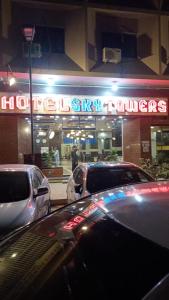 ein Geschäft mit Autos, die nachts davor geparkt sind in der Unterkunft Hotel Sky Towers in Karatschi