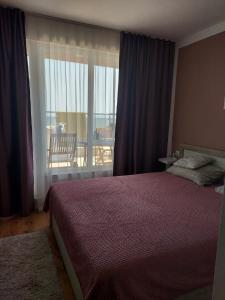 een slaapkamer met een bed en uitzicht op een balkon bij Прекраснные апартаменты с панорамным видом на море in Byala