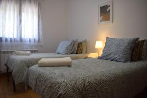 - une chambre avec deux lits, une lampe et une fenêtre dans l'établissement El Paraiso, à Tragacete
