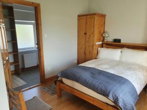 Schlafzimmer mit einem Bett mit einem Kopfteil aus Holz und einem Fenster in der Unterkunft Patricia’s Country Cottage in Sligo