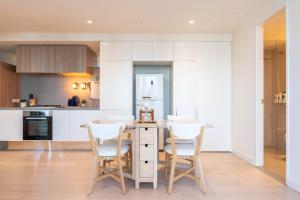 a kitchen with white cabinets and a table and chairs at Cozy & spacious 2B2B APT in CBD in Melbourne