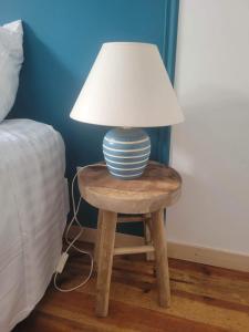 une lampe sur une table en bois à côté d'un lit dans l'établissement Petite maison avec jardin privé, au Malzieu-Ville