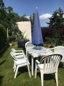 une table avec un parasol bleu et quatre chaises blanches dans l'établissement Petite maison avec jardin privé, au Malzieu-Ville 1 autre photo