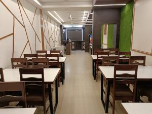 a dining room with tables and chairs and a chalkboard at Hotel Satyam in Jaigaon