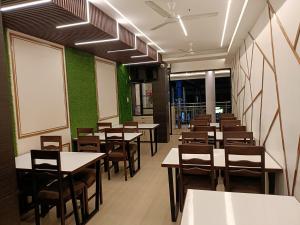 a dining room with tables and chairs and a whiteboard at Hotel Satyam in Jaigaon