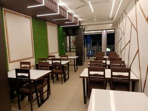 una sala da pranzo con tavoli e sedie e pareti verdi di Hotel Satyam a Jaigaon