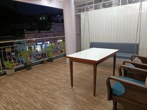 a table and a bench in a room with potted plants at Hotel Satyam in Jaigaon