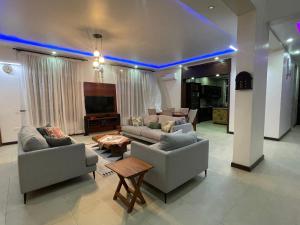 uma grande sala de estar com sofás e uma televisão em Dar Villa em Dar es Salaam