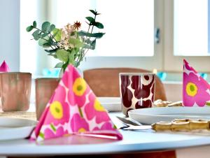 uma mesa com pratos e um vaso com flores em Nordic Quality Apartments- Feel the North em Rovaniemi