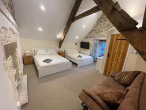 a bedroom with two beds and a couch at Large Historic Farmhouse in Rhondda Valley Perfect for Groups with Hot Tub in Blaencwm