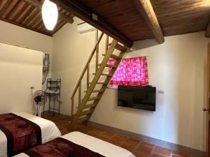 a room with two beds and a staircase and a television at Yong Le Homestay in Jincheng