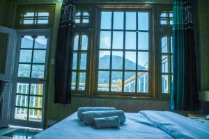 ein Bett mit zwei Kissen in einem Zimmer mit Fenstern in der Unterkunft JOYstels Kasol in Kasol