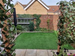 a garden with a lawn in front of a brick wall at 31 Elwyn Road in March