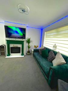 a living room with a green couch and a flat screen tv at White House Villa in Nottingham