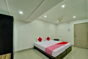 een witte kamer met een bed met rode kussens bij Super OYO Flagship Hotel Shakti Inn in Jamshedpur