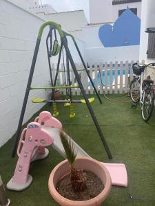 eine kleine Topfpflanze in einem Topf neben einem Spielplatz in der Unterkunft Apartamento in Sanlúcar de Barrameda