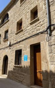 un edificio de piedra con una puerta marrón y una señal azul en Casa Nostra Matarranya, en Calaceite