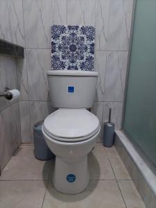 a bathroom with a toilet with a blue and white pattern at MB's Chillspot in Saint Annʼs Bay