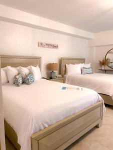 1 dormitorio con 2 camas con sábanas blancas en Tres Palmas by La Cambija en Rincon