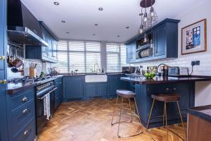 a blue kitchen with wooden floors and blue cabinets at Cosy Eton Escape with parking. in Eton