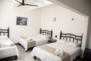 a bedroom with three beds with white sheets at Marqués Oaxaca - Hotel in Oaxaca City