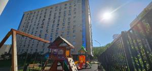 une aire de jeux en face d'un grand bâtiment dans l'établissement One Bedroom Apartment Next To Arbat In The Heart of Almaty, à Almaty