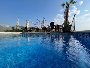 a swimming pool with chairs and a palm tree at Apart Lux Beciragic in Dobra Voda