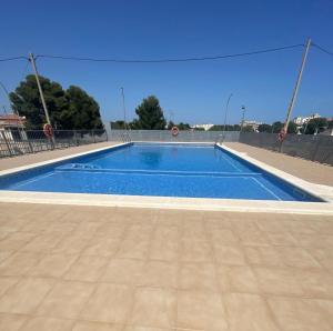 a blue swimming pool with a fence and a blue at Apartamento en Miami Platja - Tarragona in Miami Platja +14 photos