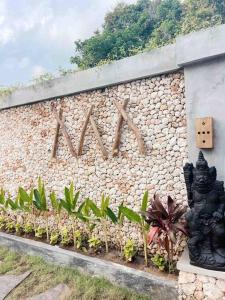 a stone wall with a wooden sign on it at Angatu Villas 2 Padang Padang in Uluwatu