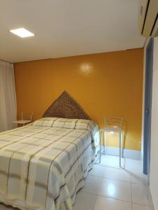 1 dormitorio con cama y pared amarilla en Apartamento Duna Barcane 1801, en Natal