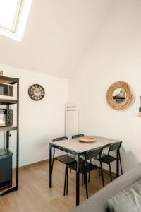 una mesa y sillas en una sala de estar con reloj en Loft du Pain avec SPA privatif, en Druye