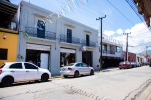 deux voitures blanches garées devant un bâtiment dans l'établissement Marqués Oaxaca - Hotel, à Oaxaca