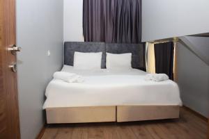 1 cama con sábanas blancas y almohadas en una habitación en Avist Hotel Avcılar, en Avcılar