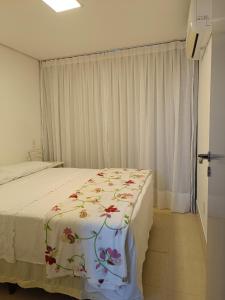 Un dormitorio con una cama con una manta floral. en Apartamento Duna Barcane 1801, en Natal