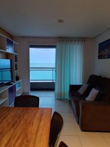 a living room with a table and a large window at Apartamento Duna Barcane 1801 in Natal