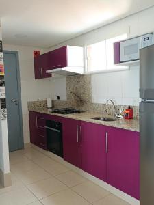 a kitchen with purple cabinets and a sink at Apartamento Duna Barcane 1801 in Natal