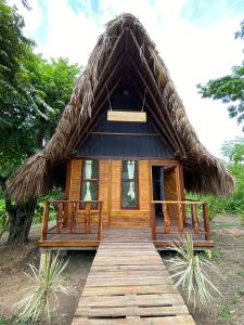 Cabaña pequeña con techo de paja y pasarela de madera en Ecohab -Parque Tayrona, en Santa Marta