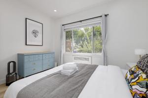 a white bedroom with a bed and a window at Spacious Fully Furnished 2-BR Suite in Vancouver