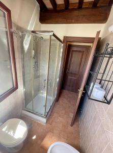 La salle de bains est pourvue d'une douche en verre et de toilettes. dans l'établissement Saturnia House, à Poggio Murella