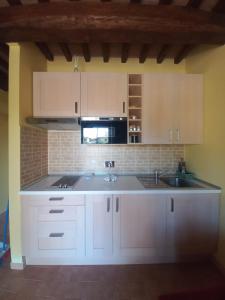 una cocina con armarios blancos y fregadero en Saturnia House, en Poggio Murella