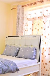 Un dormitorio con una cama con almohadas moradas y una ventana en Haven Luxury Homes, en Kitengela 
