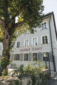 ein weißes Gebäude mit einem Baum davor in der Unterkunft Gasthof Zantl in Bad Tölz