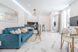uma sala de estar com um sofá azul e uma cozinha em Renovated Apt Min. from Beach/Palais - 30m2 Terrace em Cannes