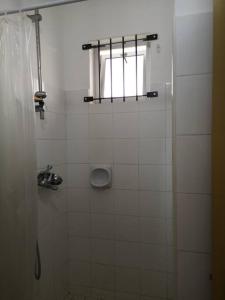 W łazience znajduje się prysznic wyłożony białymi kafelkami oraz okno. w obiekcie My lîl Place rental unit in a beach facing complex w mieście Flic-en-Flac