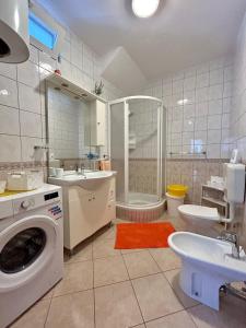 a bathroom with a toilet a sink and a washing machine at Apartments Korta in Račišće
