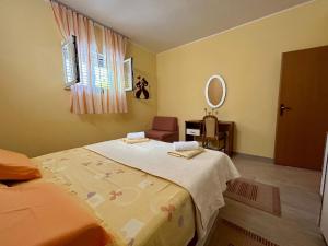 a bedroom with a bed and a chair and a mirror at Apartments Korta in Račišće