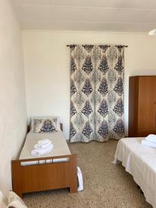 1 dormitorio con 2 camas y una ventana con cortina en La Chiocciola - Casa vacanze, en Erice
