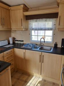 a kitchen with wooden cabinets and a sink and a window at Seaview in Skegness